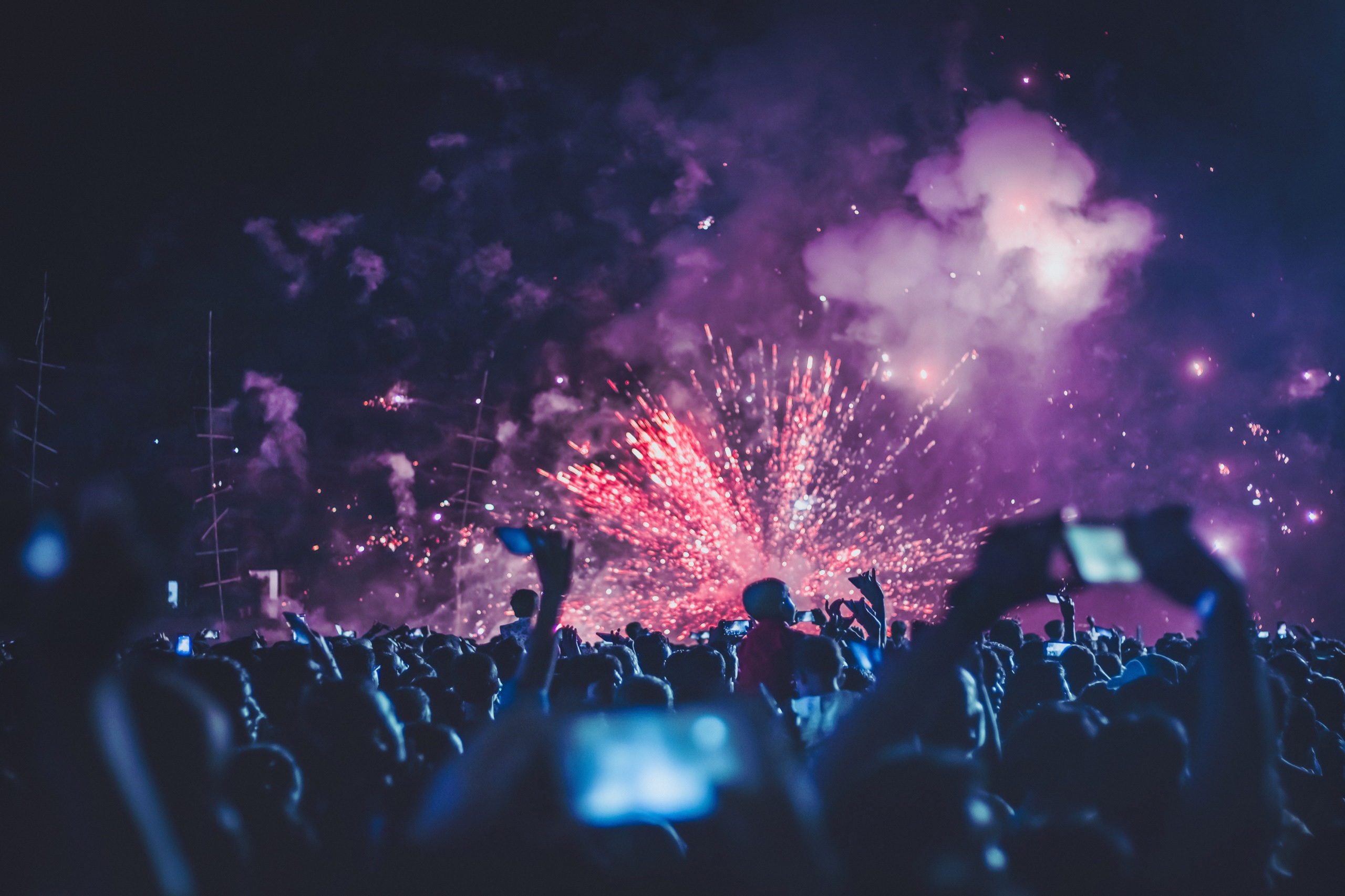 A nighttime festival crowd watching purple fireworks above the stage